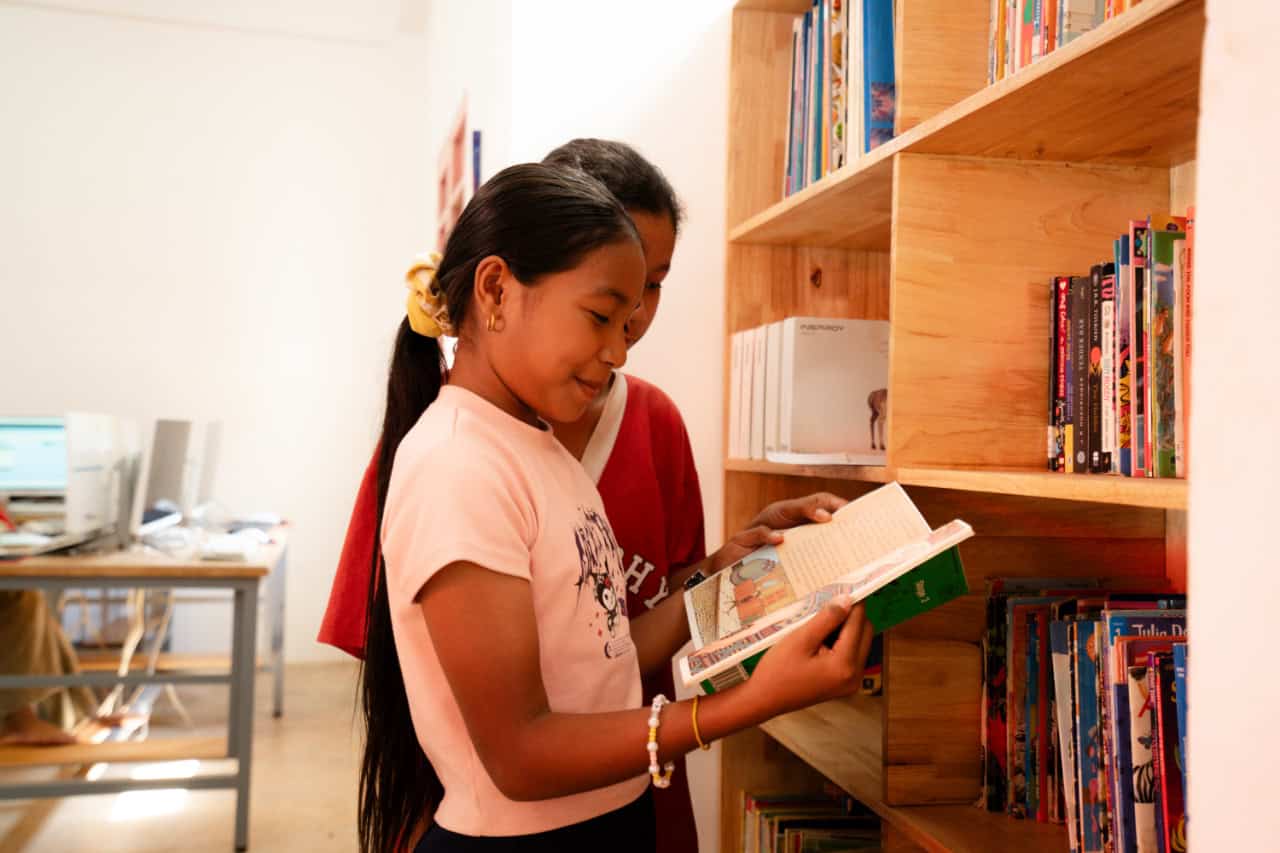 Students Reading a Book in a Library
